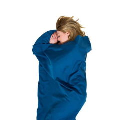 Sieviete guļ Lifeventure PolyCotton Sleeping Liner guļammaisā uz balta fona